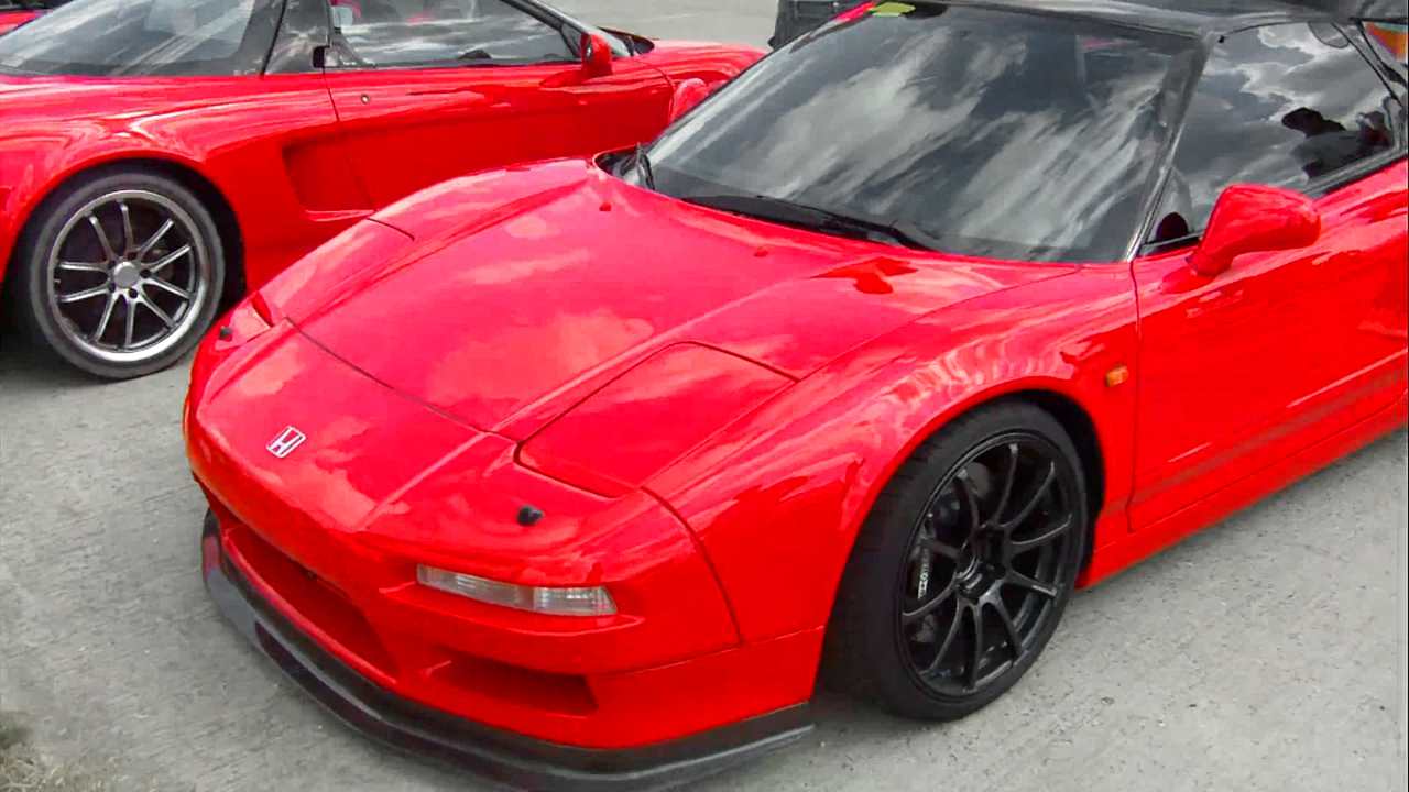 Two red honda NSX cars at a car show.
